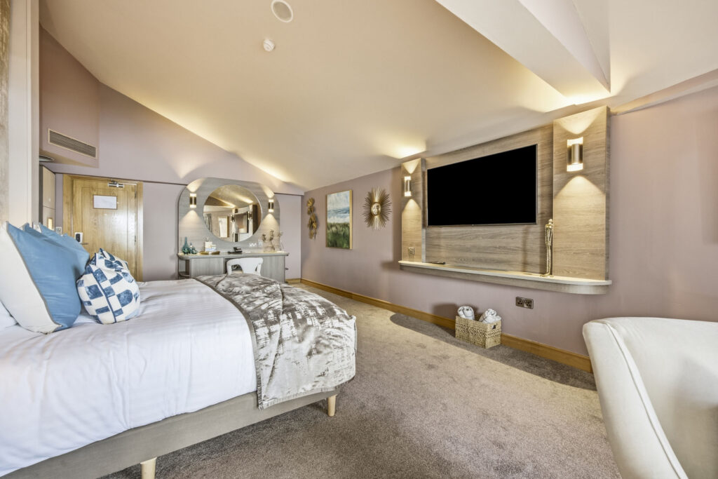 Luxurious hotel room with plush bedding, large flat-screen TV, elegant decor, and spacious layout. Perfect for relaxation.