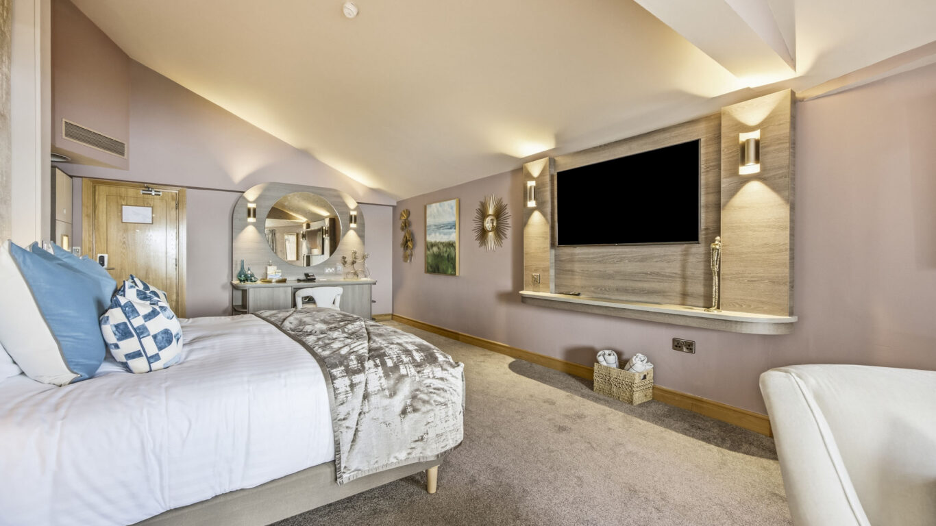 Luxurious hotel room with plush bedding, large flat-screen TV, elegant decor, and spacious layout. Perfect for relaxation.