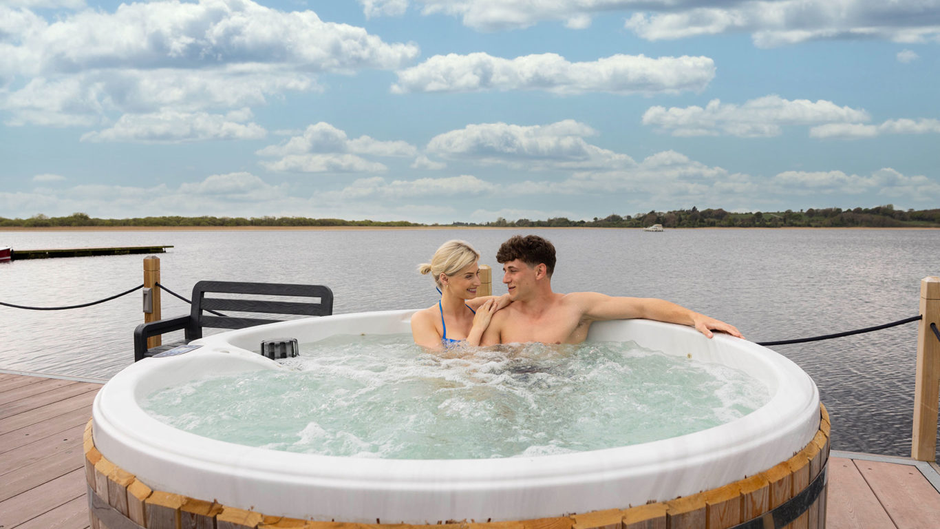 Couple relaxing in a lakeside hot tub, enjoying picturesque views and serene atmosphere at a luxury hotel retreat.