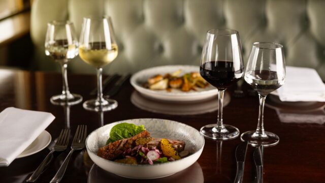 Elegant hotel dining with gourmet dishes and exquisite wine pairings on a polished table, set for a memorable dinner.