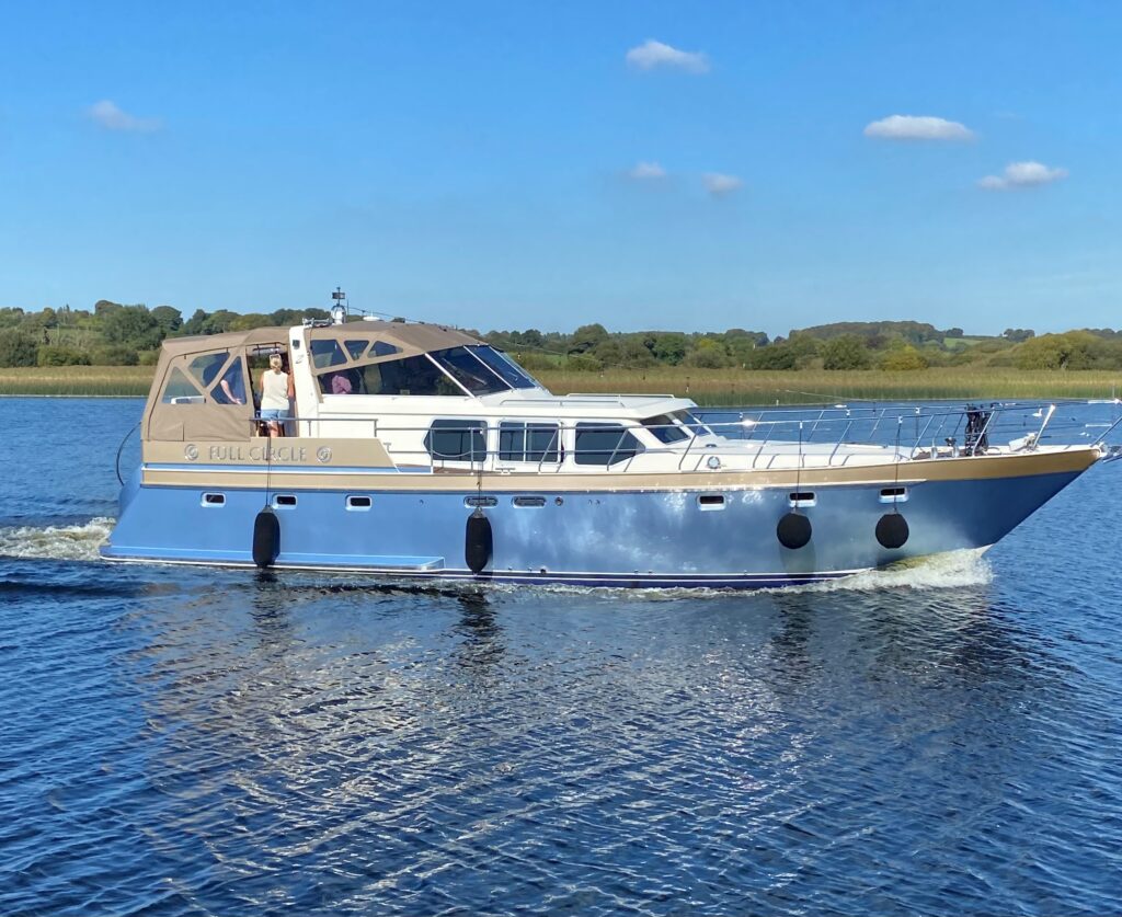 Luxurious boat gliding on tranquil waters with scenic countryside views, offering a relaxing escape with comfortable amenities.