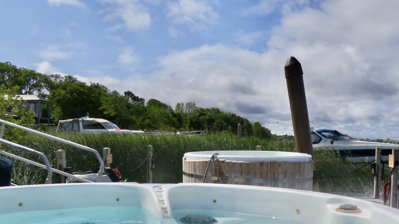 Luxurious hot tub with tranquil waterfront view, perfect for relaxation amidst lush greenery at our scenic hotel.