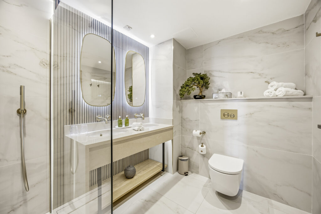 Elegant hotel bathroom with marble design, dual mirrors, rainfall shower, and plush towels for a luxurious stay.