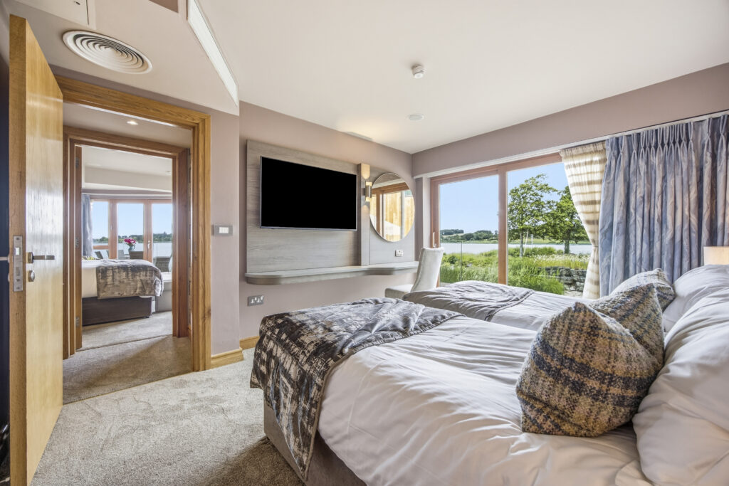 Spacious hotel room with lake view, twin beds, modern décor, and a flat-screen TV, offering a serene and cosy stay.
