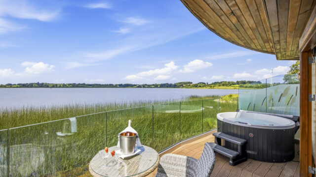 Luxurious lake view balcony with private hot tub and seating, perfect for relaxation and scenic nature enjoyment.